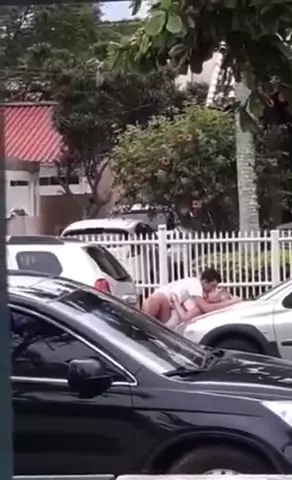 Flagra quente de um casal se amarrando no capô do carro no meio do centro da cidade