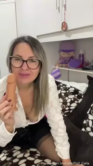 Professora Carla mamando um pau de borracha com uma expressão sedutora