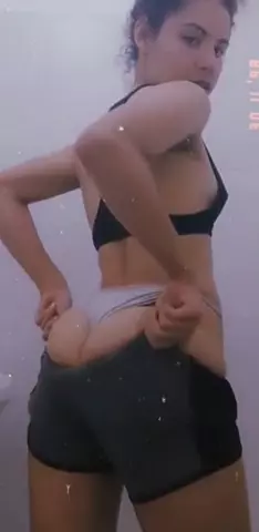 Mulher usando um short de ginástica sexy fazendo uma transmissão ao vivo escondida e se exibindo